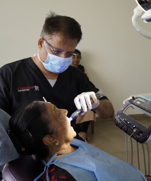 A dental expert wearing a black shirt and mask is conducting a dental examination on a woman's teeth.