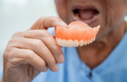 A person holding a denture that helps as a convenient and flexible solution for missing teeth.