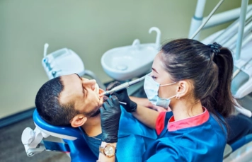 A woman dentist examines the dental patient for guided implant surgery using specific tools.